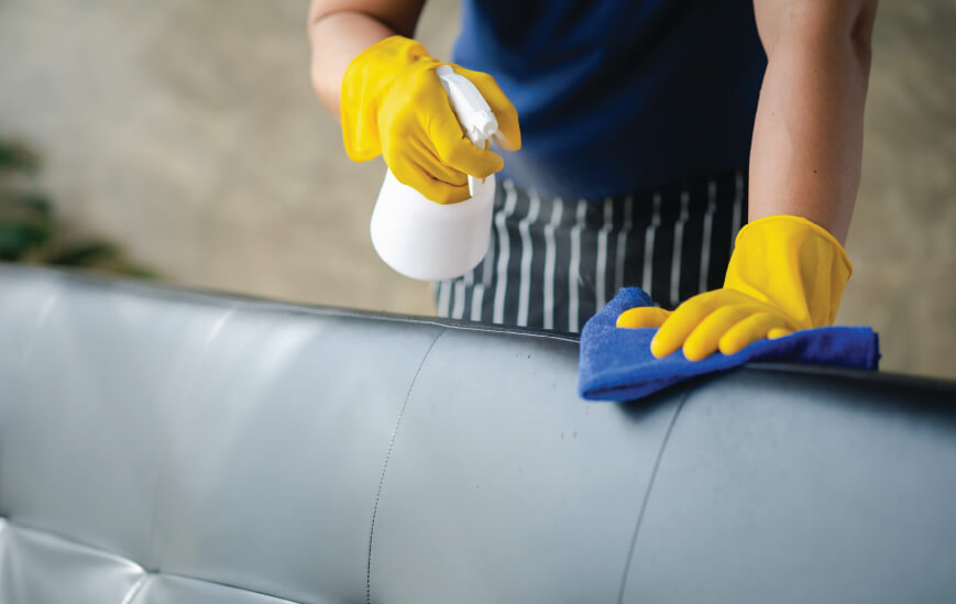 Housekeeper wearing glove with cleaning supplies.