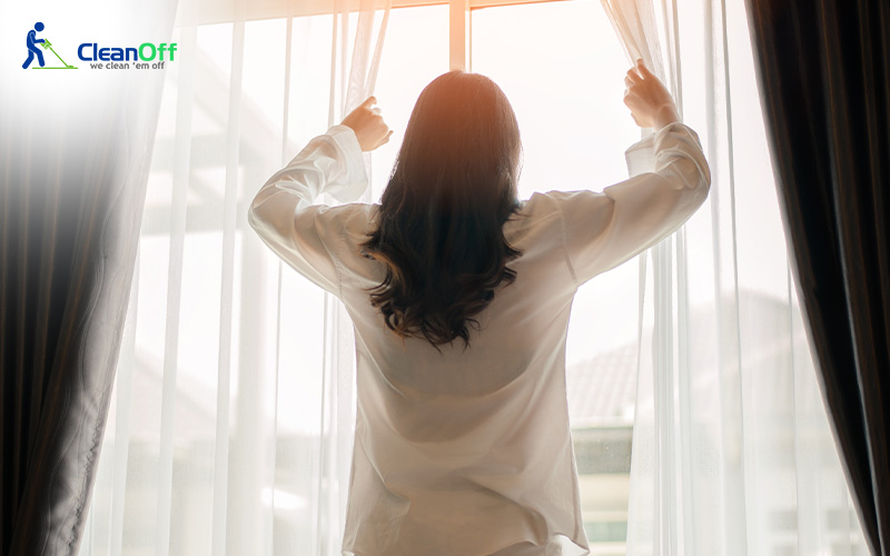 Woman opening curtains to let sunlight in